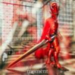 Solo Leveling crimson knight cosplay by @sirjuliuscosplay at Anime NYC 2025 Javits Center, featuring full red armor, horned helmet, flowing cape, golden sword, and dramatic mirrored aura effect – animenyc.com.