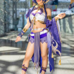 Candace cosplay from Genshin Impact by @yatappy at Anime NYC 2025 Javits Center, featuring indigo wig, golden circlet, blue and gold desert warrior outfit with tassels and jeweled belt – animenyc.com.
