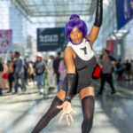 @ravenderoseig as Yoruichi Shihouin from Bleach striking a combat pose at Anime NYC 2025 Javits Center – animenyc.com.