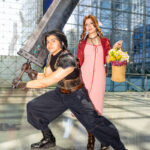 @cocofashionistagal as Aerith Gainsborough with flower basket and @aabccosplays as Zack Fair wielding the Buster Sword from Final Fantasy VII at Anime NYC 2025 Javits Center – animenyc.com.