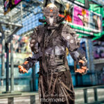 @grumpus_cosplay dressed as Maelstrom from Cyberpunk 2077 in detailed cyberpunk armor with red optic mask and chains at Anime NYC 2025 Javits Center – animenyc.com.
