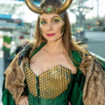 Cosplayer @michellefoard dressed as Lady Loki poses at New York Comic Con 2025, wearing a green and gold corset, horned helmet, and fur-trimmed cape under bright natural light at the Javits Center.