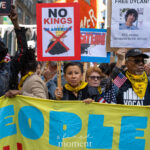 Congresswoman Nydia Velázquez holds a red “NO KINGS IN AMERICA” sign beside protesters carrying a “FREE DYLAN” poster and a large yellow banner during the No Kings March in New York City on October 18, 2025.