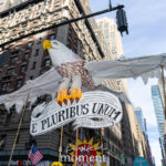 A large puppet of a bald eagle with outstretched wings and a banner reading “E PLURIBUS UNUM” is held high above protesters during the No Kings March in Midtown Manhattan on October 18, 2025.