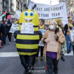 A protester in a bee costume with a sign that reads “I Only Sting Fascists” marches beside others holding signs and banners during the No Kings March in New York City on October 18, 2025.