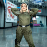 Cosplayer @ashley1auren dressed as Yelena Belova (Black Widow) from Marvel at New York Comic Con 2025, wearing an olive-green tactical suit and striking a confident pose inside the Javits Center.