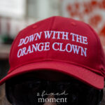 Close-up of a protester wearing a red hat that reads “Down With the Orange Clown” during the No Kings March in New York City.