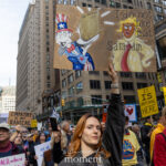 Protester holds a colorful sign showing Uncle Sam holding the Constitution and a caricature of Donald Trump with the phrase “I do not like that, Sam I am” at the No Kings March in New York City.