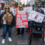Group of protesters, including veterans, hold handmade signs at the No Kings March in New York City, one reading “ORANGE IS NOT IN THE RED WHITE AND BLUE.”