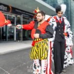 Cosplayers @joey_cupcake and @adoniss dressed as the Queen of Hearts and Cruella de Vil at New York Comic Con 2025 outside the Javits Center, wearing colorful and detailed Disney villain costumes.