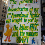 A protester holds a Sesame Street-inspired sign reading “This patriotic demonstration of our 1st Amendment Rights was brought to you by the letters FDT, and the numbers 8647!” at the No Kings March in New York City.