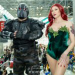 Cosplayer @devinrodriguez80 as Bane and another cosplayer as Poison Ivy from Batman at New York Comic Con 2025, posing in detailed costumes inside the Javits Center in NYC.