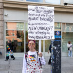 Protester in Hello Kitty overalls holding a large humorous sign that reads “Oh nooo... are we sooo scaawwy?... Vewwy scawwy march?” during the No Kings March in New York City.