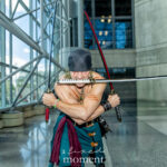 Cosplayer @chrisisonthehunt as Roronoa Zoro from One Piece performing the Three-Sword Style pose with two swords in hand and one in his mouth at New York Comic Con 2025 inside the Javits Center.
