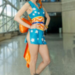 Cosplayer @hotgluehime as Nami from One Piece, wearing a turquoise kimono with orange and white accents, posing inside the Javits Center at New York Comic Con 2025.