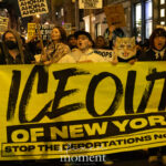 Protesters hold a large yellow banner that says “ICE OUT OF NEW YORK – STOP THE DEPORTATIONS NOW!” while marching at night during the ICE OUT of NYC protest in Manhattan on October 22, 2025.