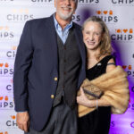 A smiling couple dressed in formal evening attire poses in front of the CHiPS banner at the 2025 Annual Gala in Park Slope, Brooklyn.