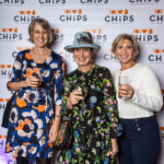 Three women holding drinks and smiling in front of the CHiPS banner at the 2025 Annual Gala in Park Slope, Brooklyn.