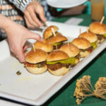 Close-up of small sliders being arranged on a tray by hand at the 2025 CHiPS Annual Gala in Park Slope, Brooklyn.