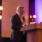 Actor David Costabile speaking into a microphone at a podium during the 2025 CHiPS Annual Gala in Park Slope, Brooklyn.