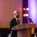 A man in a suit speaking at a podium during the 2025 CHiPS Annual Gala at 501 Union in Park Slope, Brooklyn.