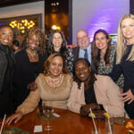 A group of eight smiling guests gathered around a table at the CHiPS Annual Gala 2025 at 501 Union in Brooklyn.