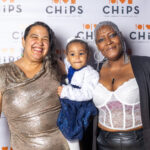 Two women and a child smiling together in front of the CHiPS step-and-repeat banner at the 2025 CHiPS Annual Gala in Brooklyn.