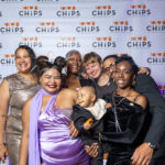 Group of smiling guests, including a baby, posing in front of the CHiPS step-and-repeat banner at the 2025 CHiPS Annual Gala in Brooklyn.
