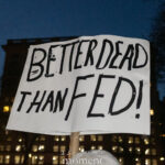 Protest sign reading “Better Dead Than Fed!” held at a nighttime demonstration in New York City.