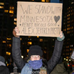 Protester holding a sign reading “We Stand With Minnesota” during a nighttime rally in New York City.