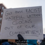 Handwritten protest sign calling for racist and untrained goons to be removed from communities at a New York City demonstration.
