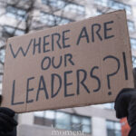 Cardboard protest sign reading “Where are our leaders?” held above a crowd during an anti-ICE march in New York City.