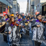 Mariachi musicians wearing patterned ponchos play violins and guitars while marching during the Hands Off protest on January 11, 2026, in Midtown Manhattan.