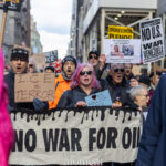 Protesters chanting with ICE = Terror sign and No War for Oil banner at Hands Off protest in New York City.
