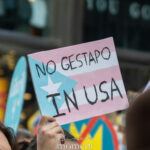 Hand-painted protest sign reading “No Gestapo in USA” over a trans pride–inspired flag design at a New York City protest.