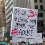 Close-up of a protest sign reading The Call Is Coming From Inside the White House during a New York City demonstration.