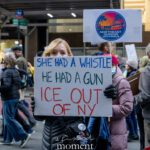 Protester holding sign that reads “She Had a Whistle, He Had a Gun, ICE Out of NY” at a New York City demonstration.