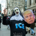 Protester in a horror-style nun mask and ICE shirt holding a Donald Trump face cutout during a New York City protest.