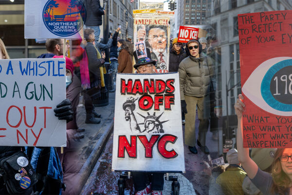 Composite image of protesters marching through Midtown Manhattan holding signs that read “Hands Off NYC,” “ICE Out of NY,” and a reference to 1984 during a large, peaceful demonstration opposing ICE enforcement and federal policies under Donald Trump.