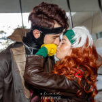 Gambit and Rogue cosplayers kissing in close portrait wearing brown leather jackets and green and yellow gloves at Dragon Con 2025 in Atlanta, GA. Cosplayer @plaisance_plays_songz.