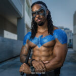 Nightwing cosplay from DC Comics with blue chest emblem, black mask, and escrima stick at Dragon Con 2025 in Atlanta, GA. Cosplayer @keithkelleytv.