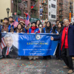 Assemblyman Lester Chang stands in front of supporters holding a banner with his name during the Lunar New Year Parade in Chinatown, New York City.