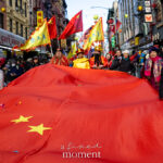 A group of parade participants carry a large red Chinese flag through Chinatown during the Lunar New Year Parade in New York City.