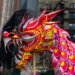 Close-up of a bright red and pink dragon head used in a Lunar New Year parade performance in Chinatown, New York City.