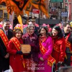 Governor Kathy Hochul and Mayor Zohran Mamdani stand with community leaders as a participant holds a plaque during the Lunar New Year Parade in Chinatown, New York City.