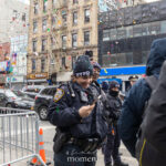 NYPD officers wearing winter hats stand near metal barricades as confetti falls during the Lunar New Year Parade in Chinatown, New York City.