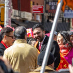 Mayor Zohran Mamdani smiles while wearing a red sash and speaking with attendees during the Lunar New Year Parade in Chinatown, New York City.
