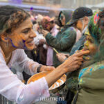 Anu Sehgal, founder of The Culture Tree, gently applies orange Holi powder to a child’s face during the Festival of Colors celebration at Pier 17 in New York City.