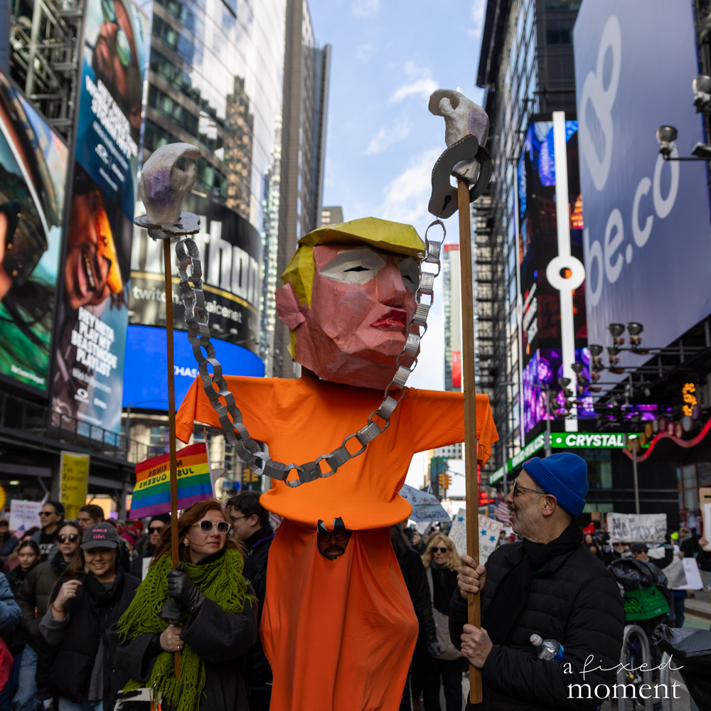 A large puppet depicting Donald Trump with chains is carried through Times Square during the No Kings protest.