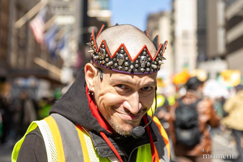 A protest volunteer wearing a decorative crown and headset smiles during the No Kings protest in Manhattan.